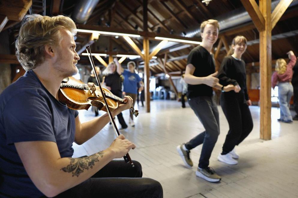 Unge danser på loftet og en man spiller fiolin