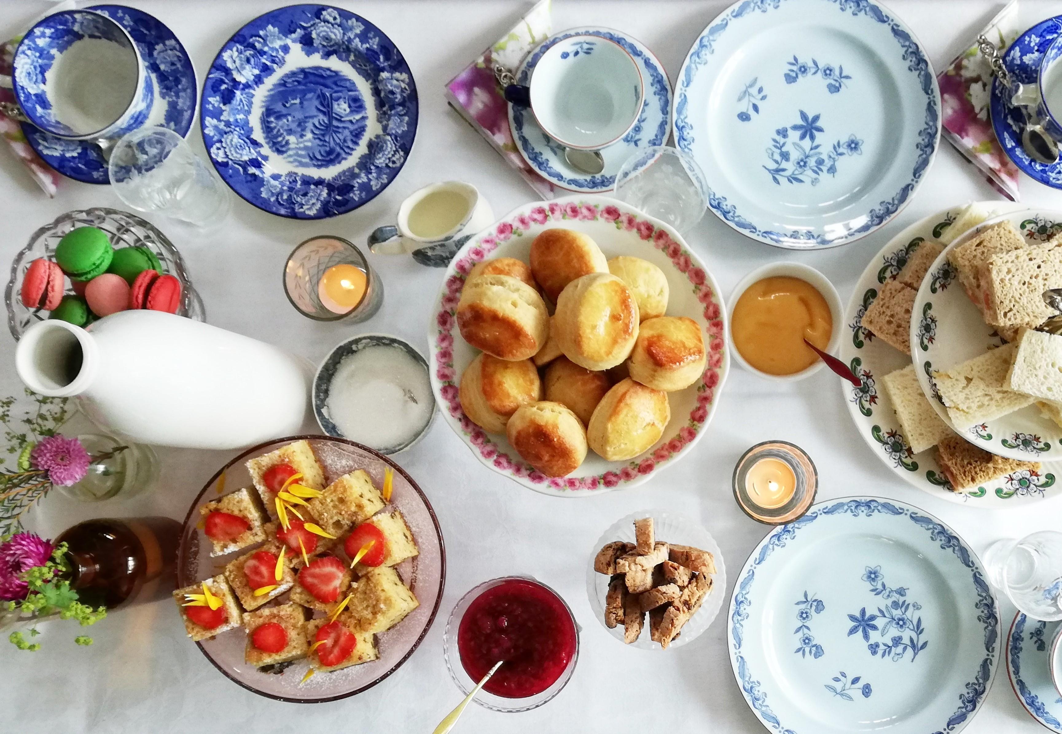 A table set with all the trimmings for a proper English Afternoon Tea. Picture taken from above with scones, sandwiches, biscotti, macarons etc.