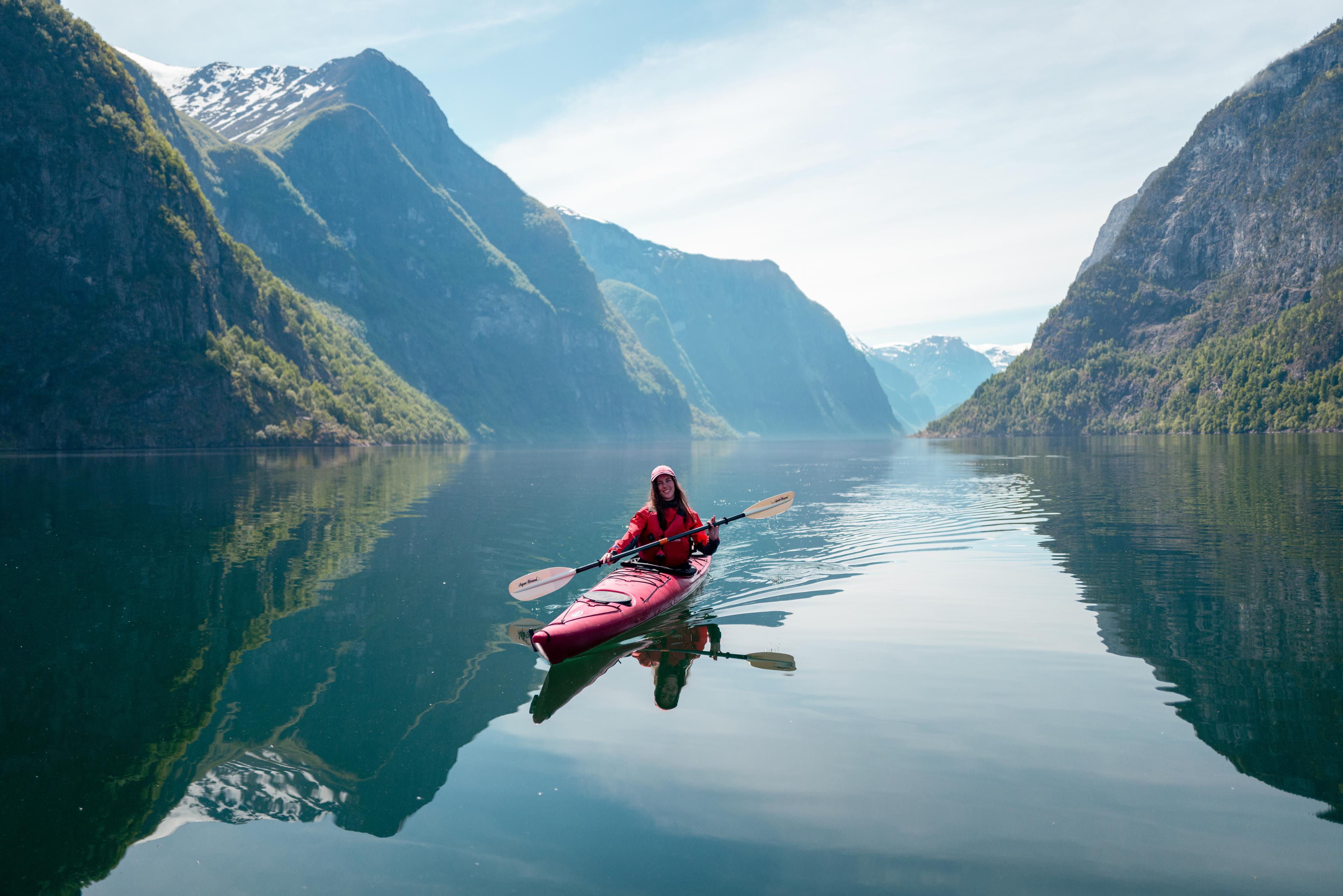 Kvinner kjenner seg springfull mens hun padler på fjorden